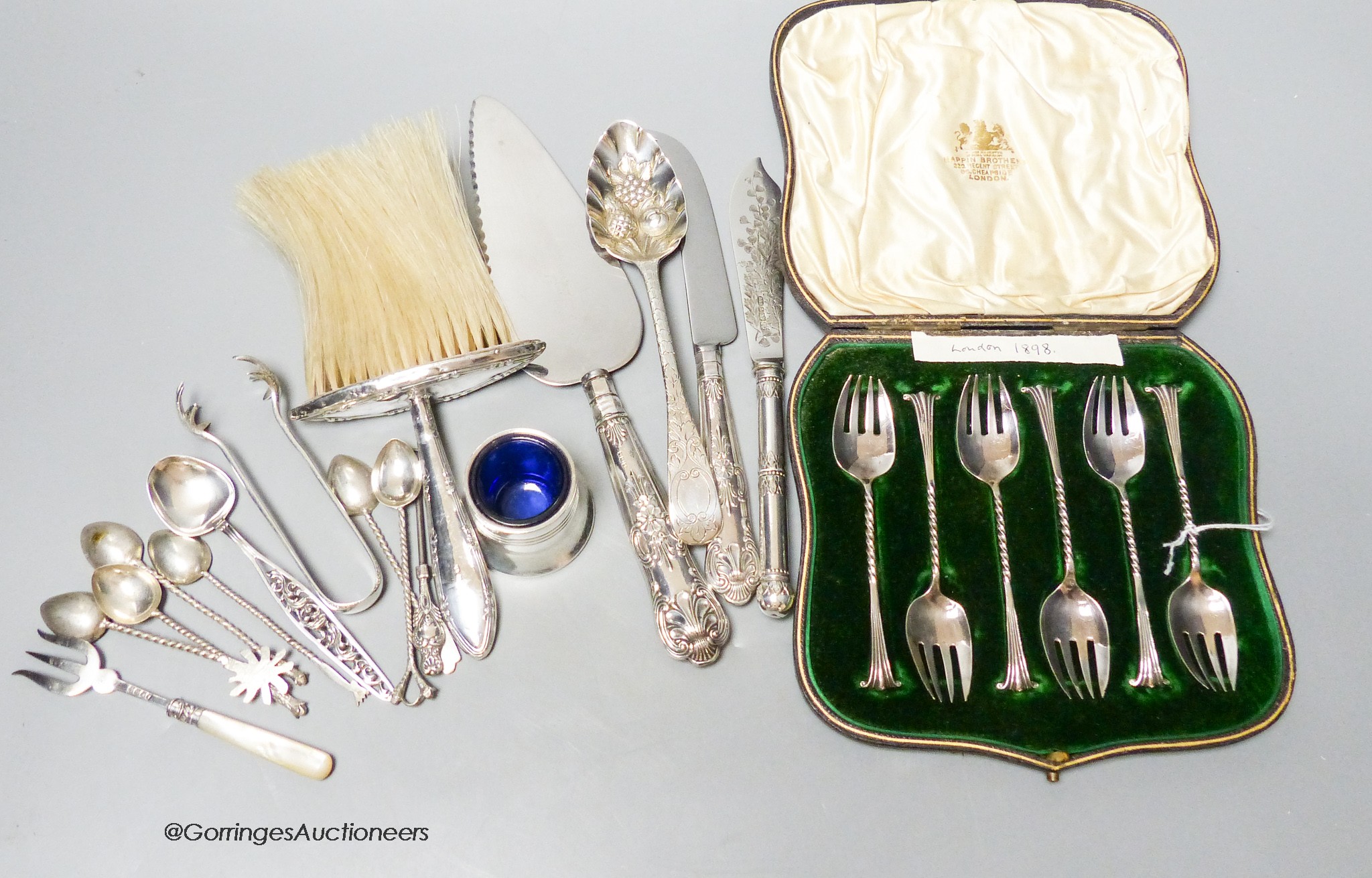 A set of six Victorian silver cake forks, a George III silver berry spoon (later embossed), a pair of silver sugar tongs and a spoon and sundry items